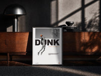 Black-framed Basketball Dunk Motivation print on the floor in front of a dark wooden console