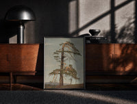 Black-framed gnarled windblown pine tree against sky vintage art print print on a moody console with designer…