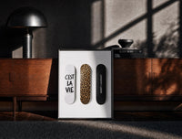 Black-framed Saint Laurent Cest La Vie Skateboards framed poster print on a moody console with designer coffee-table books