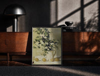 Black-framed flowers and lemons still life vintage art print print on a moody console with designer coffee-table books