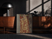Black-framed Klimt's Hygieia with gold serpent vintage art print print on a moody console with designer coffee-table books
