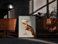 Black-framed Cream Coupe in Hand print on the floor in front of a dark wooden console