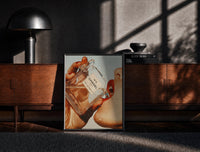 Black-framed Luxury Fragrance Portrait framed poster print on a moody console with designer coffee-table books