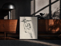 Black-framed mother embracing seated daughter vintage art print print on a moody console with designer coffee-table books