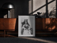 Black-framed crowned queen seated portrait vintage art print print on a moody console with designer coffee-table books