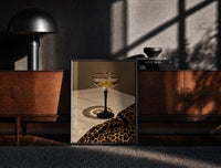 Black-framed Champagne Coupe with Leopard Print on the floor in front of a dark wooden console