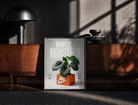 Black-framed Nike Monstera Sneaker Box Green framed poster print on a moody console with designer coffee-table books