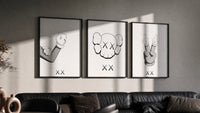 KAWS Companion Middle Finger triptych in three black frames on a grey wall above a leather sofa