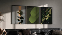 Nike Botanical framed poster set of 3 triptych in three black frames on a grey wall above a leather sofa