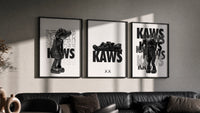KAWS Legacy Archive triptych in three black frames on a grey wall above a leather sofa