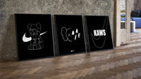 KAWS Companion XX Nike framed poster set of 3 three-piece set leaning on parquet beside a vintage loft door