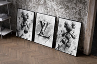 KAWS LV Monochrome Splash XX set of three black-framed prints leaning against a raw-plaster wall