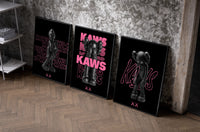 Neon Pink Noir KAWS XX set of three black-framed prints leaning against a raw-plaster wall