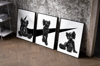 KAWS x Nike Monochrome Companion framed poster set of 3 set of three black-framed prints leaning against a raw-plaster wall
