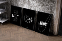 KAWS Companion XX Nike framed poster set of 3 set of three black-framed prints leaning against a raw-plaster wall