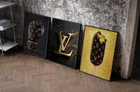 Louis Vuitton Pop Art set of three black-framed prints leaning against a raw-plaster wall