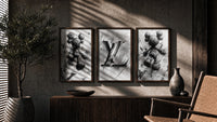 KAWS LV Monochrome Splash XX triptych in three walnut frames above a sideboard in a warm room