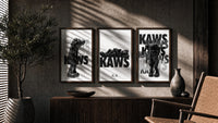 KAWS Legacy Archive triptych in three walnut frames above a sideboard in a warm room