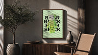 Green Glow Skeleton Bearbrick poster framed above a fluted sideboard beside a potted tree