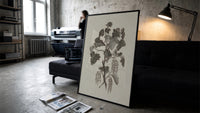 engraved currant branch study vintage art print print in a slim black frame leaning on a dark sofa in a concrete print studio