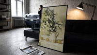 flowers and lemons still life vintage art print print in a slim black frame leaning on a dark sofa in a concrete print studio
