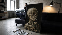 skeleton smoking a cigarette vintage art print print in a slim black frame leaning on a dark sofa in a concrete print studio