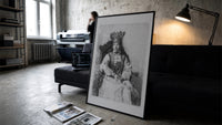 crowned queen seated portrait vintage art print print in a slim black frame leaning on a dark sofa in a concrete print studio