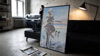 ice skaters on a frozen lake among snowy pines vintage art print print in a slim black frame leaning on a dark sofa in a…
