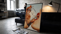 Luxury Fragrance Portrait framed poster print in a slim black frame leaning on a dark sofa in a concrete print studio