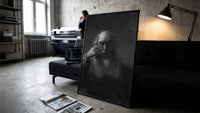 elderly bearded man in shadow vintage art print print in a slim black frame leaning on a dark sofa in a concrete print studio