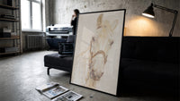 white horse head portrait with bridle vintage art print print in a slim black frame leaning on a dark sofa in a concrete…