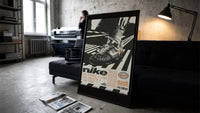 White Off-White Nike Air Force 1 framed poster print in a slim black frame leaning on a dark sofa in a concrete print studio