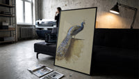 peacock with full tail perched on ledge vintage art print print in a slim black frame leaning on a dark sofa in a…