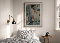 Hokusai Ono Waterfall Kiso Road print in a black frame above a bed with striped linens