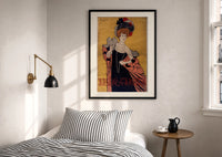Cappiello Hélène Chauvin print in a black frame above a bed with striped linens, a brass wall lamp and a sunlit window