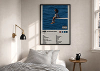 SZA SOS Album Tracklist print in a black frame above a bed with striped linens, a brass wall lamp and a sunlit window