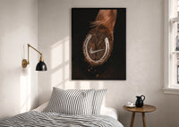 Nike Horse Hoof Swoosh Equestrian print in a black frame above a bed with striped linens