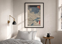 Hiroshige Meguro Bridge in Snow print in a black frame above a bed with striped linens