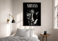 Kurt Cobain Nirvana Live print in a black frame above a bed with striped linens, a brass wall lamp and a sunlit window