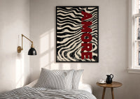 Amore Zebra Print in a black frame above a bed with striped linens, a brass wall lamp and a sunlit window