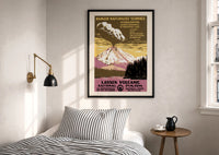 WPA Lassen Volcanic Park print in a black frame above a bed with striped linens, a brass wall lamp and a sunlit window
