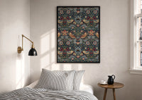 William Morris Strawberry Thief print in a black frame above a bed with striped linens