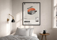 SEAxFOOD Market Original Salmon Sushi print in a black frame above a bed with striped linens