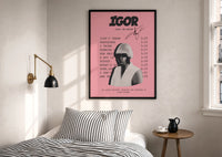 Pink Tyler, the Creator IGOR Tracklist print in a black frame above a bed with striped linens
