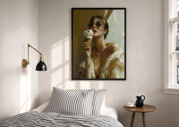 Louis Vuitton Gold Ice Cream print in a black frame above a bed with striped linens, a brass wall lamp and a sunlit window