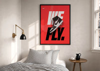 Nike Air Jordan 1 We Fly print in a black frame above a bed with striped linens, a brass wall lamp and a sunlit window
