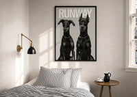 Doberman Pinscher Portrait Duo print in a black frame above a bed with striped linens, a brass wall lamp and a sunlit window