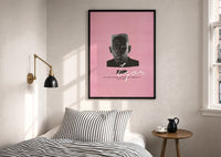 Tyler the Creator IGOR print in a black frame above a bed with striped linens, a brass wall lamp and a sunlit window