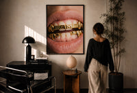 AMG Grillz Gold Grill print in a black frame on a sunlit plaster wall, a person looking on beside a mushroom lamp