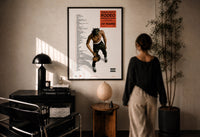 Travis Scott Rodeo Anniversary print in a black frame on a sunlit plaster wall, a person looking on beside a mushroom lamp